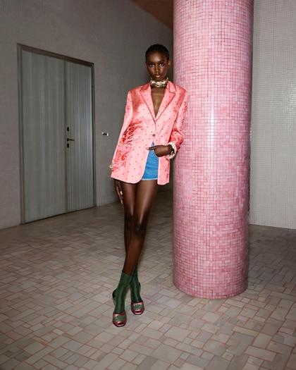 The model wears a pink paisley Etro jacket paired with blue denim shorts