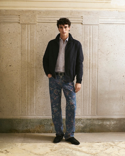 Model wearing a dark jacket, a shirt with paisley print and a floral denim pant