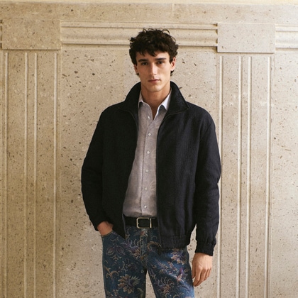 Model wearing a dark jacket, a shirt with paisley print and a floral denim pant