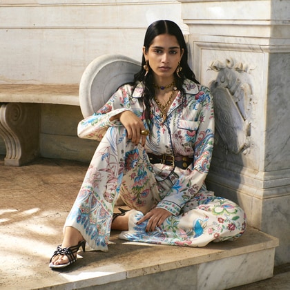 Model wearing a LONG SILK SHIRT PAIRED WITH SILK TROUSERS WITH THE SAME MOTIF: A PLACED FLORAL PRINT IN THE SHADES OF WHITE, PINK AND BLUE