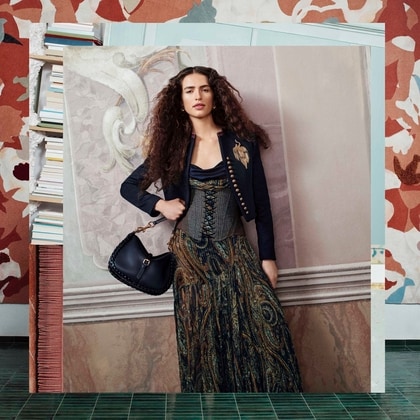 Model wearing an Etro embellished jacket, printed dress and shoulder bag.