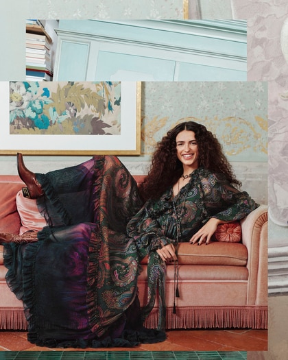 Model wearing an Etro printed dress and Etro boots seating in a sofa