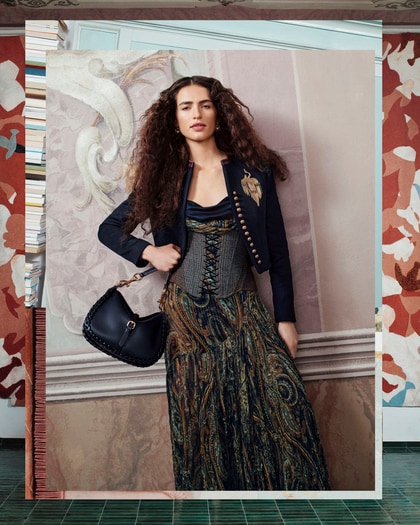 Model wearing an Etro embellished jacket, printed dress and shoulder bag.