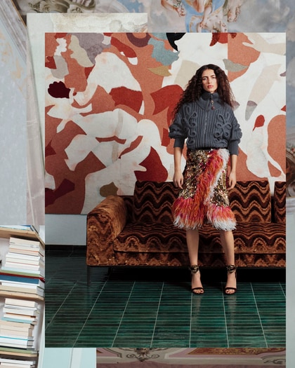 Model wearing an Etro knit sweater and colorful feathered skirt in a patterned interior.