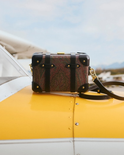 ETRO X GLOBE-TROTTER MICRO RIGID ARNICA AND LEATHER CROSSBODY BAG placed above a yellow plane