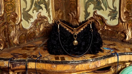 SMALL VELA BAG IN FUR placed on an elegant, baroque-inspired sofa.