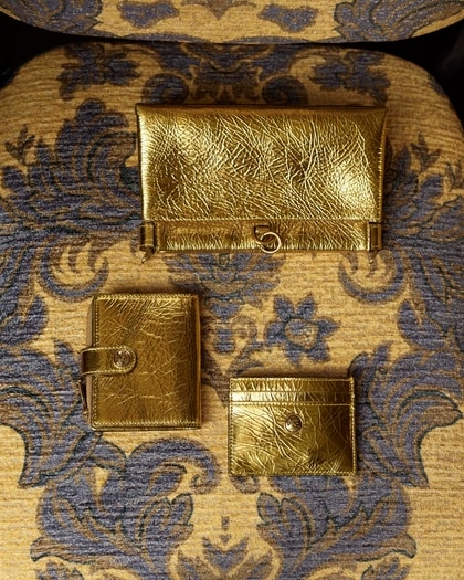 Gold laminated small leather goods on a paisley print pattern