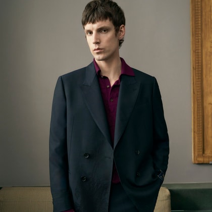 Model standing wearing an open blue double-breasted jacket by Etro, with a burgundy wool polo shirt visible underneath.