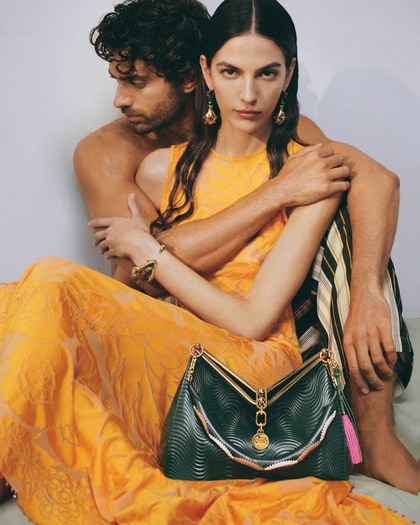 two models, woman wearing a yellow etro dress of ss25 runway collection and in front of her a Etro Vela bag