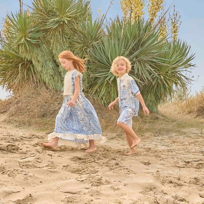 Two children wearing Etro Kids clothing of SS26 walking on the beach