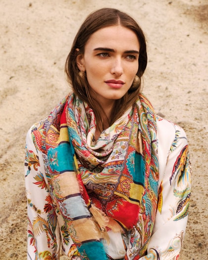 Woman wearing an Etro paisley-print shirt and multicoloured scarf, styled with statement earrings against a natural backdrop.