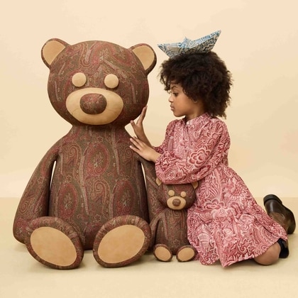 Little girl wearing CREPON DRESS WITH FLORAL PRINT hugging a teddy bear
