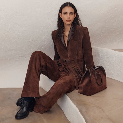 Model in a brown suede Etro suit with fringe detailing, matching wide-leg pants, and a brown suede Libra bag.